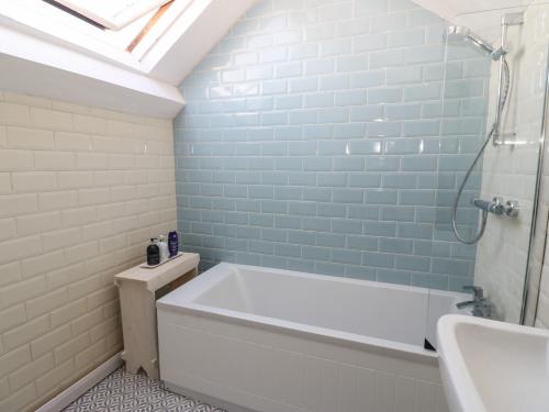 a bathroom with a bath tub and a sink at Teal Cottage in Leyburn