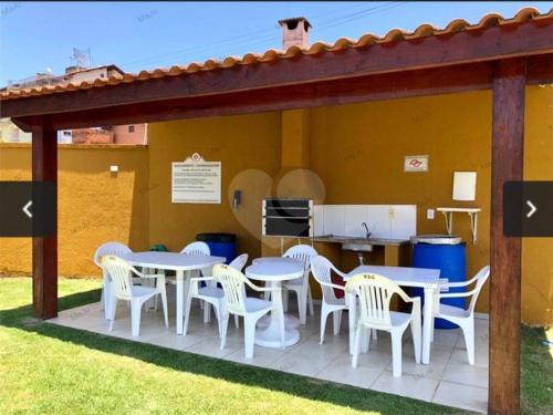 un patio con mesas blancas y sillas blancas en Casa de Praia Martins De Sá Condomínio Caraguatatuba en Caraguatatuba