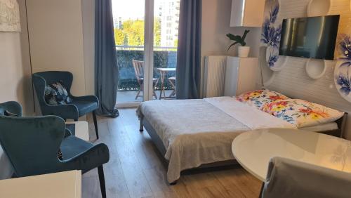 1 dormitorio con 1 cama, 2 sillas y mesa en Apartament Wyszyńskiego 10, en Białystok