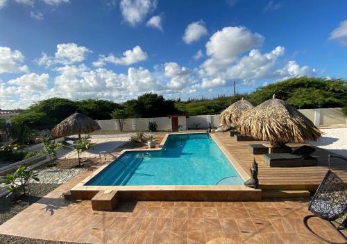 a swimming pool with umbrellas and a resort at Pura Vida Aruba appartement Cama in Noord