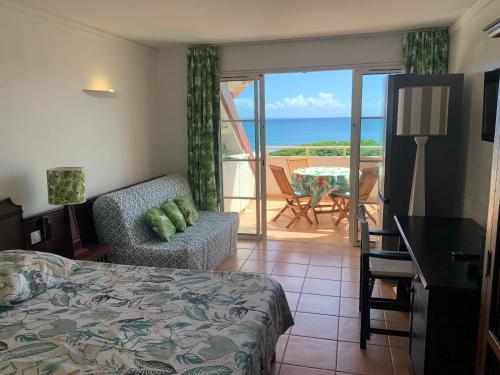 a bedroom with a bed and a balcony with the ocean at Studio Cannelle Vue Mer Village Vacances Sainte Anne in Sainte-Anne