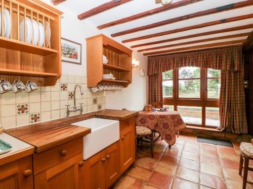 a kitchen with a sink and a table and a window at Poplar Cottage in Evesham