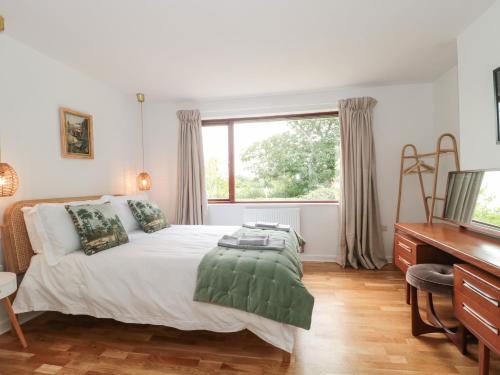 1 dormitorio con cama, escritorio y ventana en Orchard End, en Glastonbury