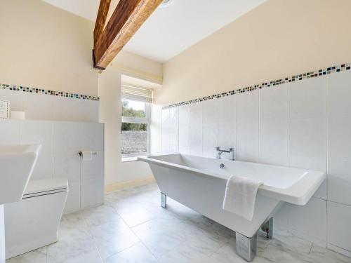 een witte badkamer met een bad en een raam bij Eden Mill, Millers Beck in Kendal