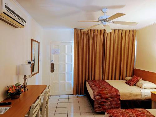 1 dormitorio con 2 camas, escritorio y ventilador de techo en Sasaki Apartments, en Palm-Eagle Beach
