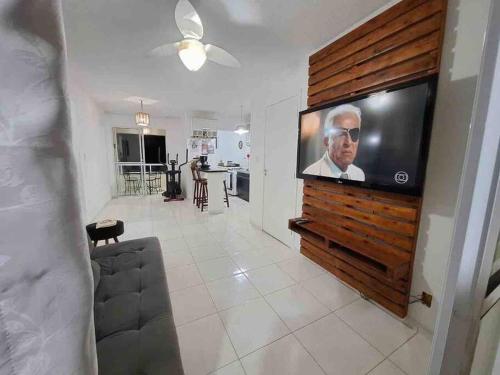 a living room with a large flat screen tv on a wall at Guarajuba - apartamento 2 quartos com suíte e piscina raia olímpica in Camacari