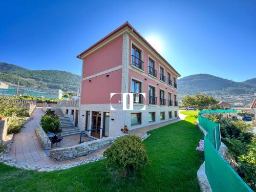 un gran edificio rosa con una valla verde en Hotel A Raiña, en Oia