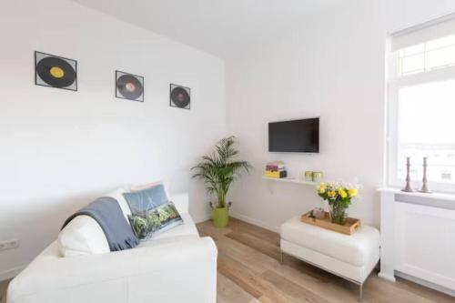 sala de estar blanca con sofá blanco y TV en BBWestduin, en La Haya