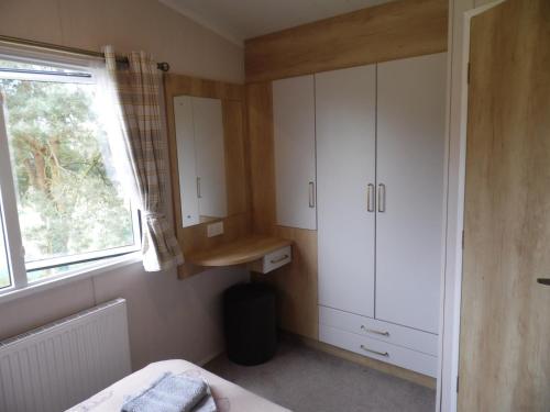 a small bedroom with white cabinets and a window at Stag Lodge in Great Yarmouth