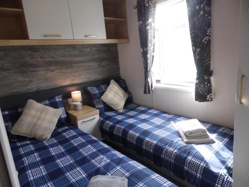 two twin beds in a small room with a window at Stag Lodge in Great Yarmouth