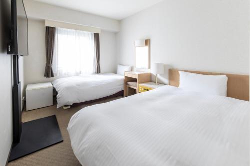 Court Hotel Niigata في نيغاتا: غرفة فندقية بسريرين ونافذة