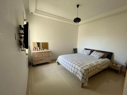 a bedroom with a bed and a dresser at appartement chic et ensoleillé ola blanca 2 in Dar Hamida