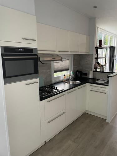 a kitchen with white cabinets and a stove top oven at Knus chalet Heidebloem in Putten