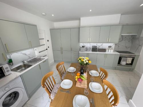 a kitchen with a wooden table with chairs and a sink at Wind and Waves Apartment by Seaside Llandudno in Llandudno
