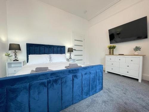 a bedroom with a blue bed and a tv at Wind and Waves Apartment by Seaside Llandudno in Llandudno