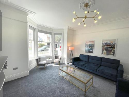 a living room with a blue couch and a table at Wind and Waves Apartment by Seaside Llandudno in Llandudno