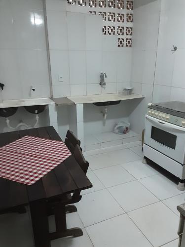 a white kitchen with a table and a stove at VERDEPERTO Camping Clube in Guarapari