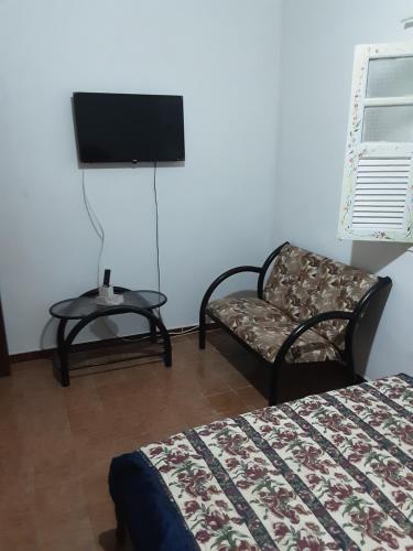 um quarto com uma cama e uma cadeira e uma televisão em VERDEPERTO Camping Clube em Guarapari