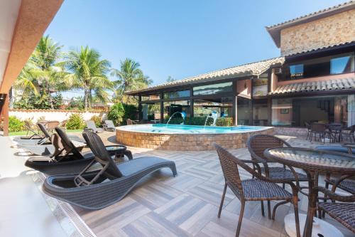 un patio al aire libre con sillas y una piscina en Pousada Marbella Inn, en Búzios