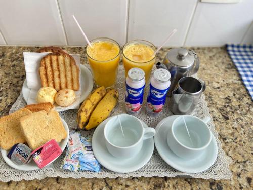 un plateau de petit-déjeuner avec du pain grillé et deux verres de jus d'orange dans l'établissement MOTEL MEDITERRÂNEO, à Lagoa Santa