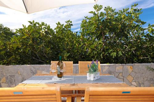 a wooden table with two chairs and a bottle of wine at Sea Point Villa Ivan in Kornić