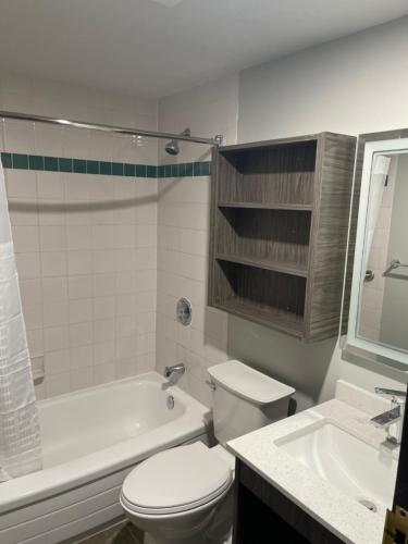 a bathroom with a toilet and a tub and a sink at Days Inn & Suites by Wyndham Summerside in Summerside