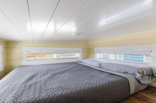 - un grand lit dans une chambre avec 2 fenêtres dans l'établissement Ruby Red Tiny Home, à Apple Valley
