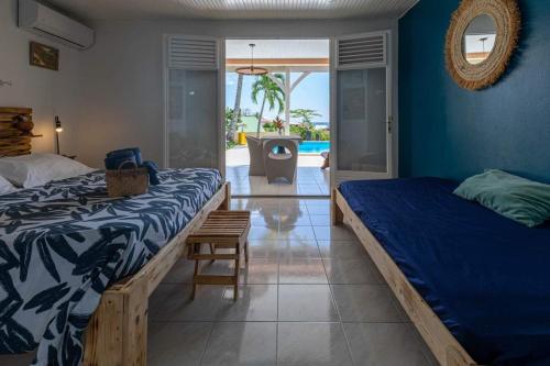 a bedroom with two beds and a view of a pool at Villa Sable et Colibris in Sainte-Luce