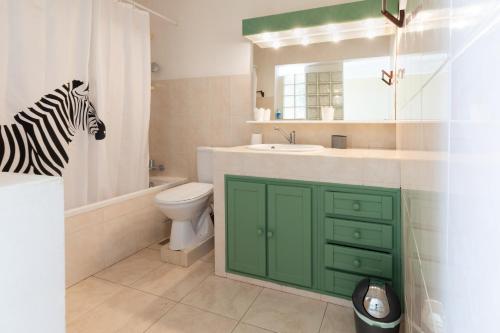 La salle de bains est pourvue d'une armoire verte, d'un lavabo et de toilettes. dans l'établissement Villa Sable et Colibris, à Sainte-Luce