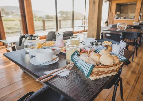 a table with a basket of bread and coffee at Hotel Puerto Madera in Pelluhue