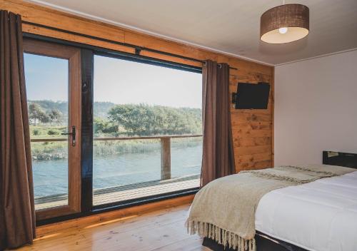 a bedroom with a bed and a large window at Hotel Puerto Madera by DOT Boutique in Pelluhue