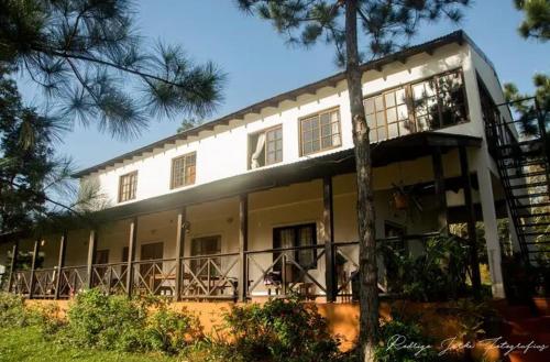een groot wit gebouw met een balkon en bomen bij La Laurina Casa de Campo Hotel/Hospedaje in Villa Lonca