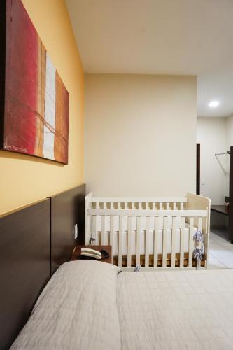 a bedroom with a crib and a painting on the wall at Attiê Park Hotel in Uberlândia