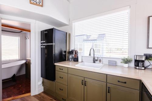 a kitchen with a sink and a black refrigerator at Moonrise Tiny Home in Apple Valley