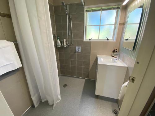 a bathroom with a sink and a shower with a window at The Ground Floor Guest Suite in Dunedin