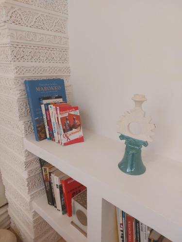 a white shelf with books and a clock on it at Dar Julia in Marrakesh