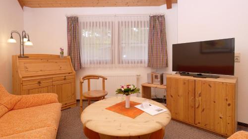 a living room with a table and a television at Hotel Residenz WALDOASE in Ahlbeck