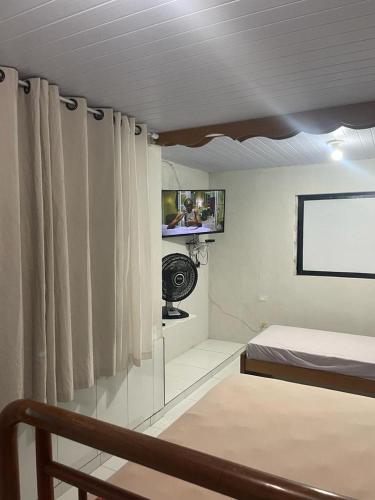 een kamer met een bed, een tv en gordijnen bij Suítes Lesther in Ubatuba