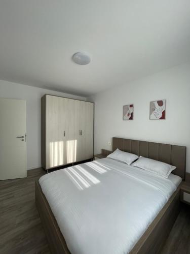 a bedroom with a large white bed and a cabinet at Comfort & Luxury Apartaments PNMresidence in Timişoara