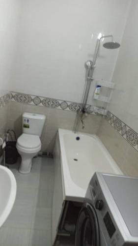 a white bathroom with a toilet and a sink at Apartment.1 in Fergana