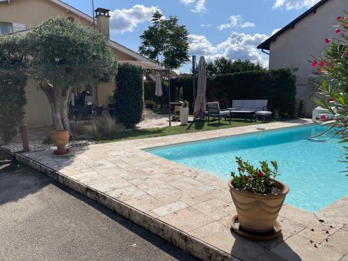 uma piscina ao lado de uma casa com um pátio em Villa individuelle - CHASSIEU em Chassieu