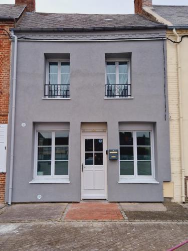 una casa gris con una puerta y ventanas blancas en La Belle Evasion, en Gamaches