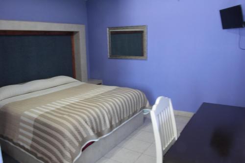 1 dormitorio con cama y pared azul en HN Hotel, en Durango