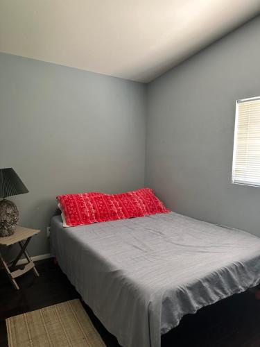 1 dormitorio con 1 cama con almohada roja en Green house, en Tecopa