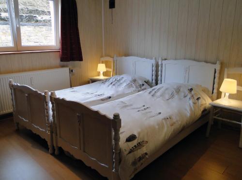 a bed in a bedroom with two lamps on tables at Le Blanc Moussi in Stavelot