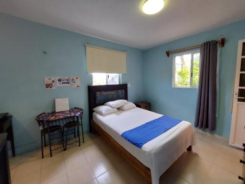 ein blaues Schlafzimmer mit einem Bett und einem Tisch in der Unterkunft Habitación Cozumel in Cozumel