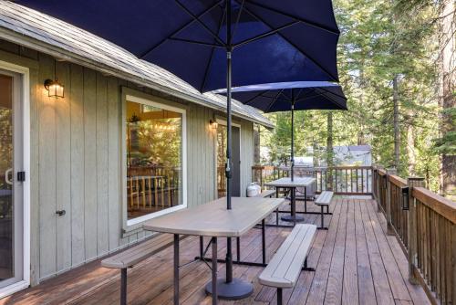 a patio with two tables and an umbrella on a deck at Cold Springs Mountain Cabin Hot Tub and Generator in Cold Springs