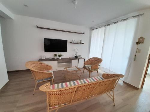a living room with wicker chairs and a table and a television at Chicama D'Amore Dpto Familiar Kids & Wave on PtoMalabrigo in Puerto Chicama