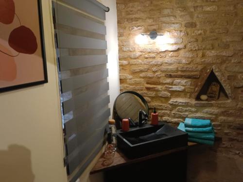 ein Bad mit einem schwarzen Waschbecken und einem Spiegel in der Unterkunft La lauze et l'anguille in Gaillac
