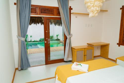 a room with a bed and a window with a pool at Pousada Coco Cabana in Camocim